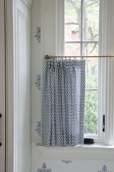 a blue and white curtain hanging on a window sill in front of a window