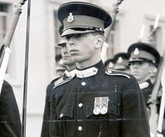 two men in uniform standing next to each other with flags on their shoulders and hands behind them