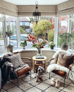 a living room filled with lots of furniture and flowers in vases on the windowsill