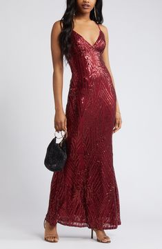 a woman wearing a red sequin gown with straps and a black handbag in her left hand