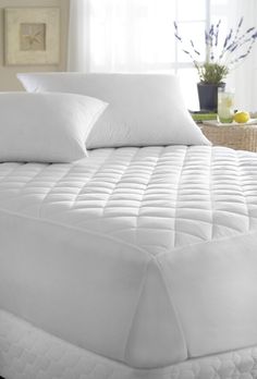 a bed with white sheets and pillows in a room