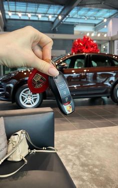 a hand holding a car key in front of a brown vehicle with a red ribbon on it