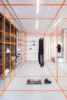 an empty room with orange scaffolding on the walls and clothes hanging in it