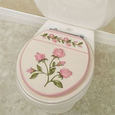 a white toilet with pink flowers painted on the lid and side panel, in a bathroom