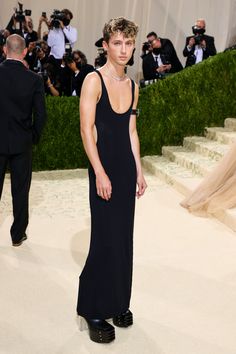 a woman in a black dress standing on a white carpet