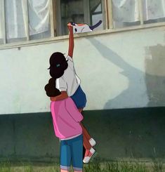 two children are playing with a kite in front of a house on the grass and one child is reaching up to catch it