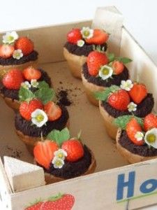 chocolate cupcakes with strawberries and flowers in a cardboard box on a table