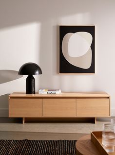 a living room scene with focus on the coffee table and art hanging over it's sideboard