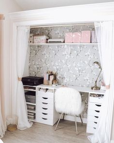 a white desk with drawers and shelves in front of a floral wallpapered wall