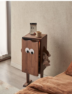 a small wooden cabinet with eyes on it's sides and a clock on top