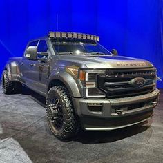 a silver truck parked in front of a blue wall with lights on it's roof