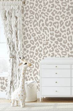 a giraffe statue sitting next to a dresser in front of a leopard print wallpaper