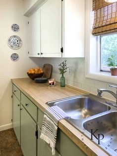 a kitchen with white cabinets and wooden counter tops next to a sink in front of a window