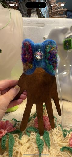 a person holding up a wooden hand with crocheted flowers on it's head