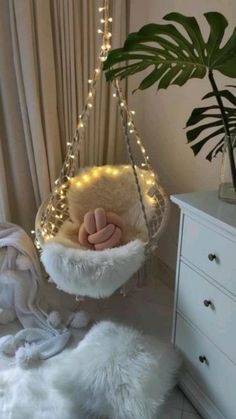 a white hammock with lights hanging from it's sides and a plant in the corner