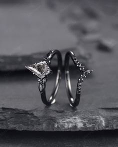 two wedding rings sitting on top of each other with stones in the middle and one diamond ring