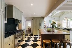 a kitchen with black and white checkered flooring, an island table and stools