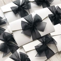 black and white cards with bows are laid out on a wooden table, next to each other