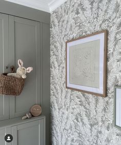 a white rabbit is hanging on the wall next to a gray cabinet with a basket