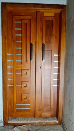 two wooden doors with metal bars on the sides and bottom, in front of a wall