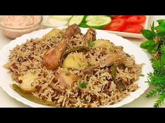 a white plate topped with rice covered in meat and veggies next to vegetables