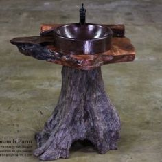 a tree stump with a bowl on it and a black candle holder in the center