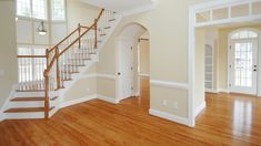 an empty room with stairs and hard wood floors