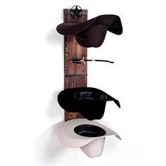 three hats are hanging on the wall with one hat in it's holder, and the other is upside down