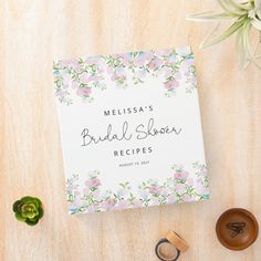 a wedding recipe book next to two rings and succulents