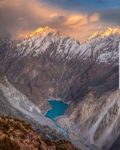 the mountains are covered in snow and there is a blue lake below that looks like it's floating in the water