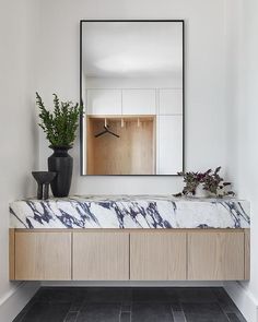 a bathroom with a marble counter top and wooden cabinetry, along with a large mirror on the wall