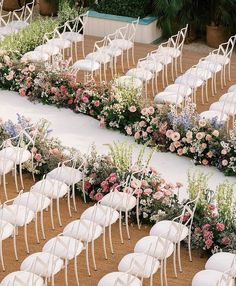 rows of white chairs with flower arrangements on them