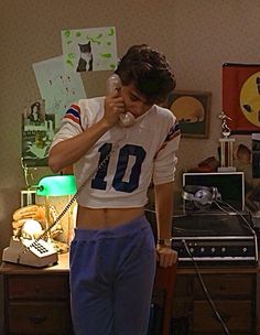 a person standing in a living room talking on a cell phone and holding a lamp