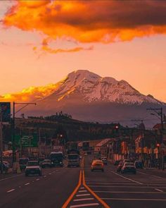 cars are driving down the road with a mountain in the backgroufground