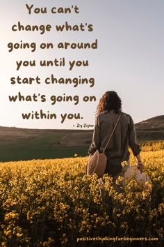 a woman walking through a field with a quote on it that says, you can't change what's going on around you until you