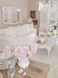 a living room filled with white furniture and pink flowers