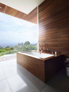 a large bath tub sitting in the middle of a bathroom next to a wooden wall