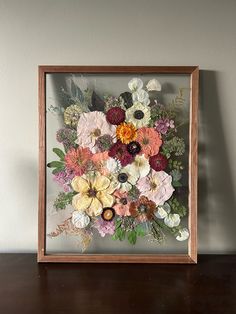 an arrangement of flowers in a wooden frame