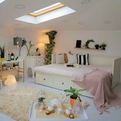 a bedroom with white furniture and lots of plants on the walls, windows, and skylights