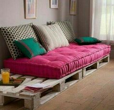 a futon sofa made out of pallets in a living room with pictures on the wall