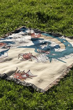 a blanket is laying on the grass with an image of a dragon painted on it