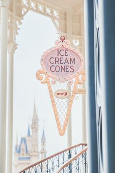 an ice cream cone sign hanging from the side of a building with a castle in the background