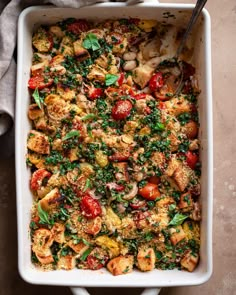 a casserole dish with tomatoes, spinach and other toppings in it