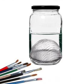 a glass jar filled with lots of paint and brushes