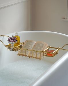 an open book is sitting in a bathtub with soap and other items on it