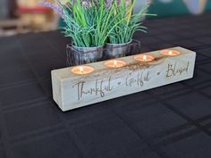 three candles are lit on a wooden block that says, thoughtful grateful and blissful