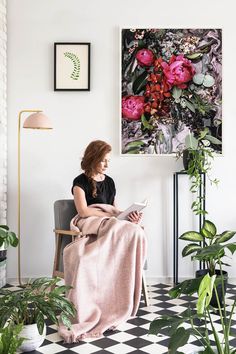 a woman sitting in a chair with a blanket on her lap looking at a magazine