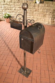 a metal mailbox sitting on top of a brick sidewalk