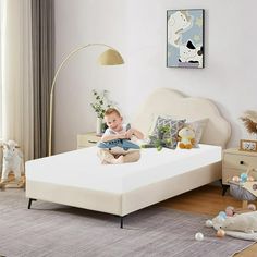 a baby is sitting on a bed in a room with toys and stuffed animals around