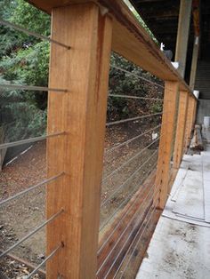 a close up of a wooden fence with wire on the top and bottom, along with trees in the background